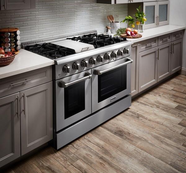 Side view of the Thor Kitchen Range 48-inch, 6.7 cu. ft. Professional Natural Gas Range in Stainless Steel, HRG4808U, with the oven door open and loaded inside, set in a modern kitchen